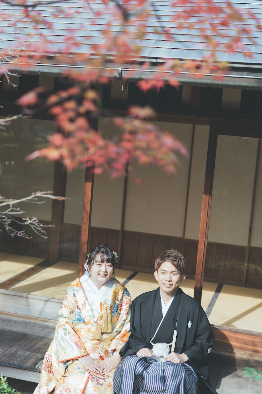 縁側で新郎と新婦が並び、紅葉を眺めている写真