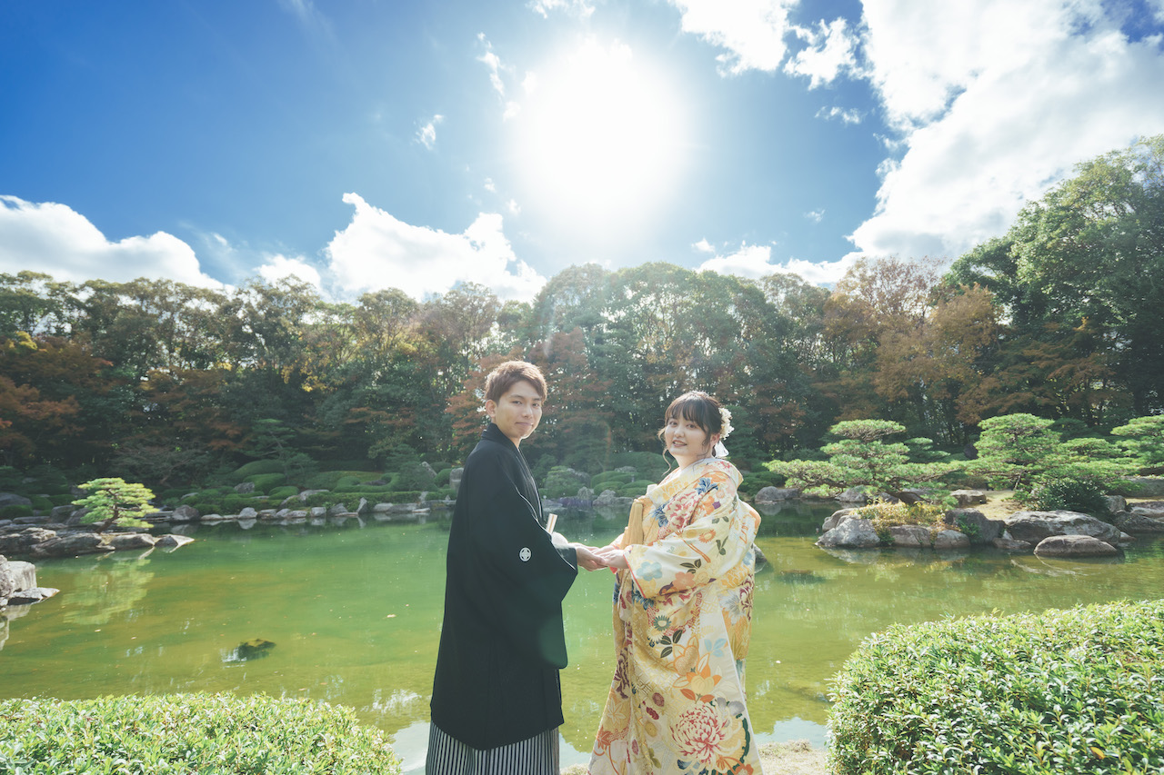 新郎と新婦が池の淵で手を繋いでいる写真