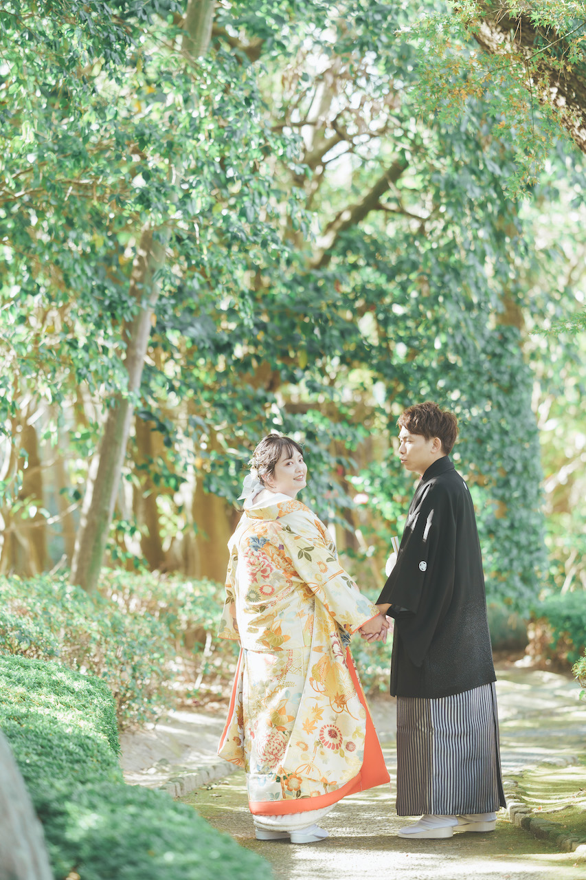 新郎と新婦が手を繋いでおり、庭園の道端で新婦が振り向いている写真