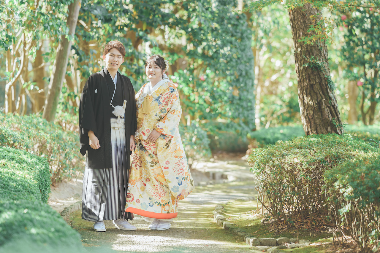 新郎と新婦が庭園の道端でこちらを見ている写真