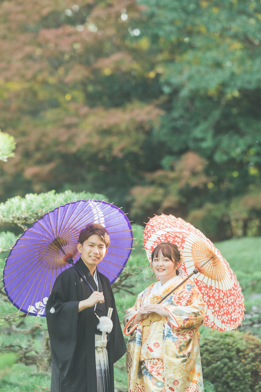 新郎と新婦が和傘をさしてこちらを見ている写真