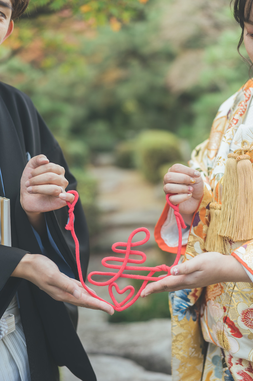 新郎と新婦が寿の形をした紐を持っている写真