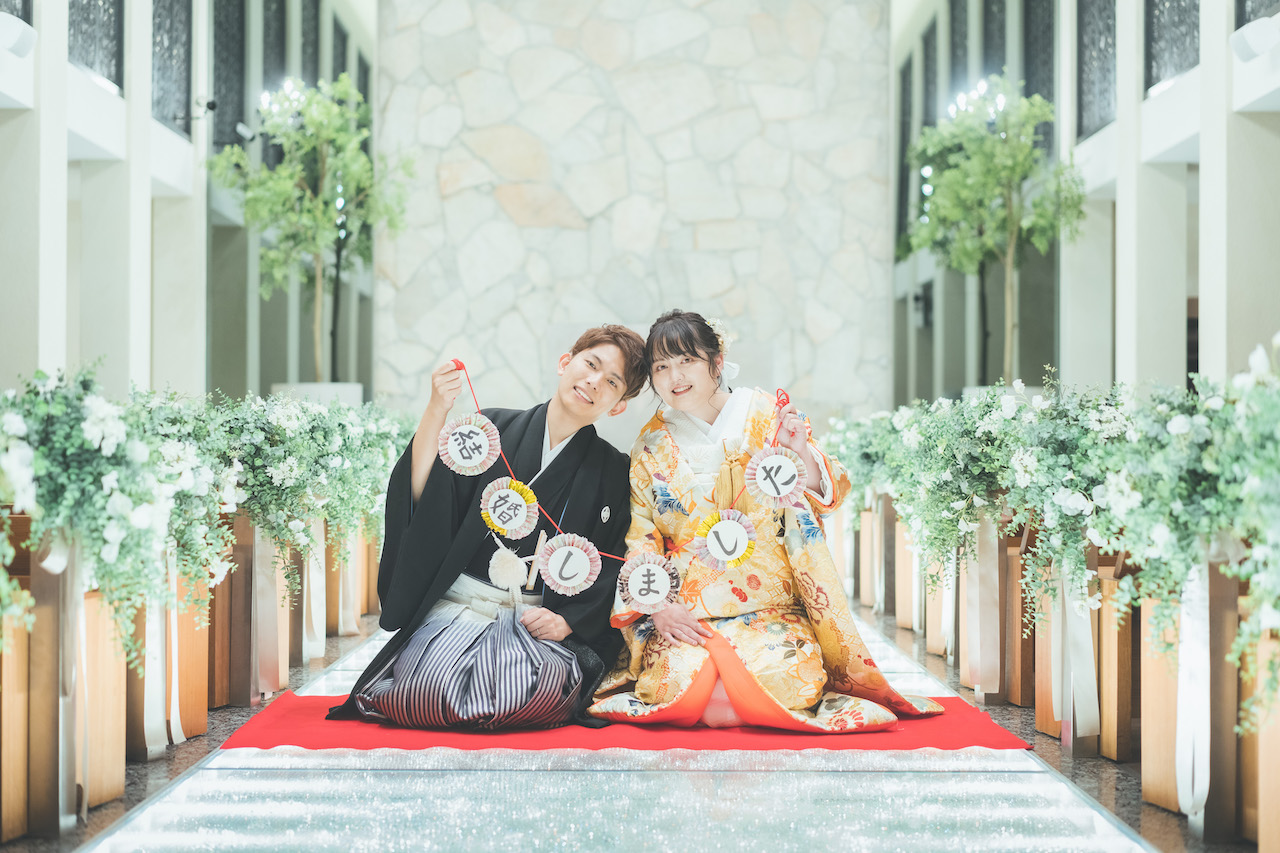 新郎と新婦が 結婚しました と書いてあるガーランドを持って座っている写真