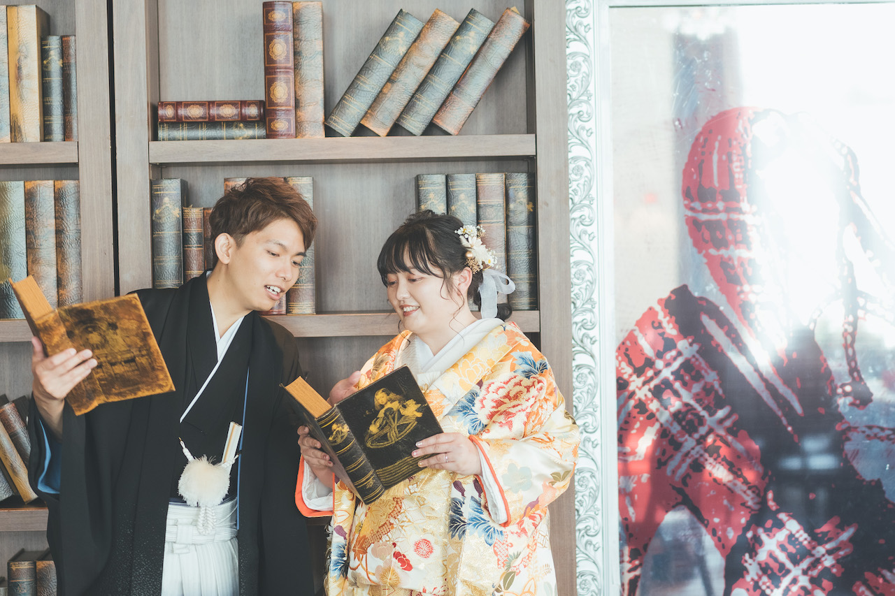 新郎と新婦が本棚の本を読んでおり、新婦の本の一部を新郎が指さしている写真