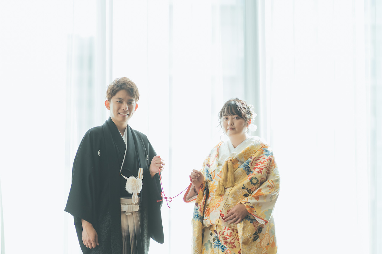 新郎と新婦が蝶々結びしている紐を持っている写真