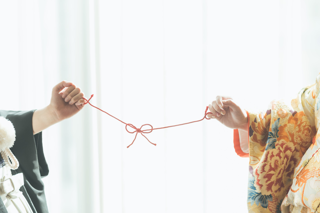 新郎と新婦が蝶々結びしている紐を引っ張り合っている写真