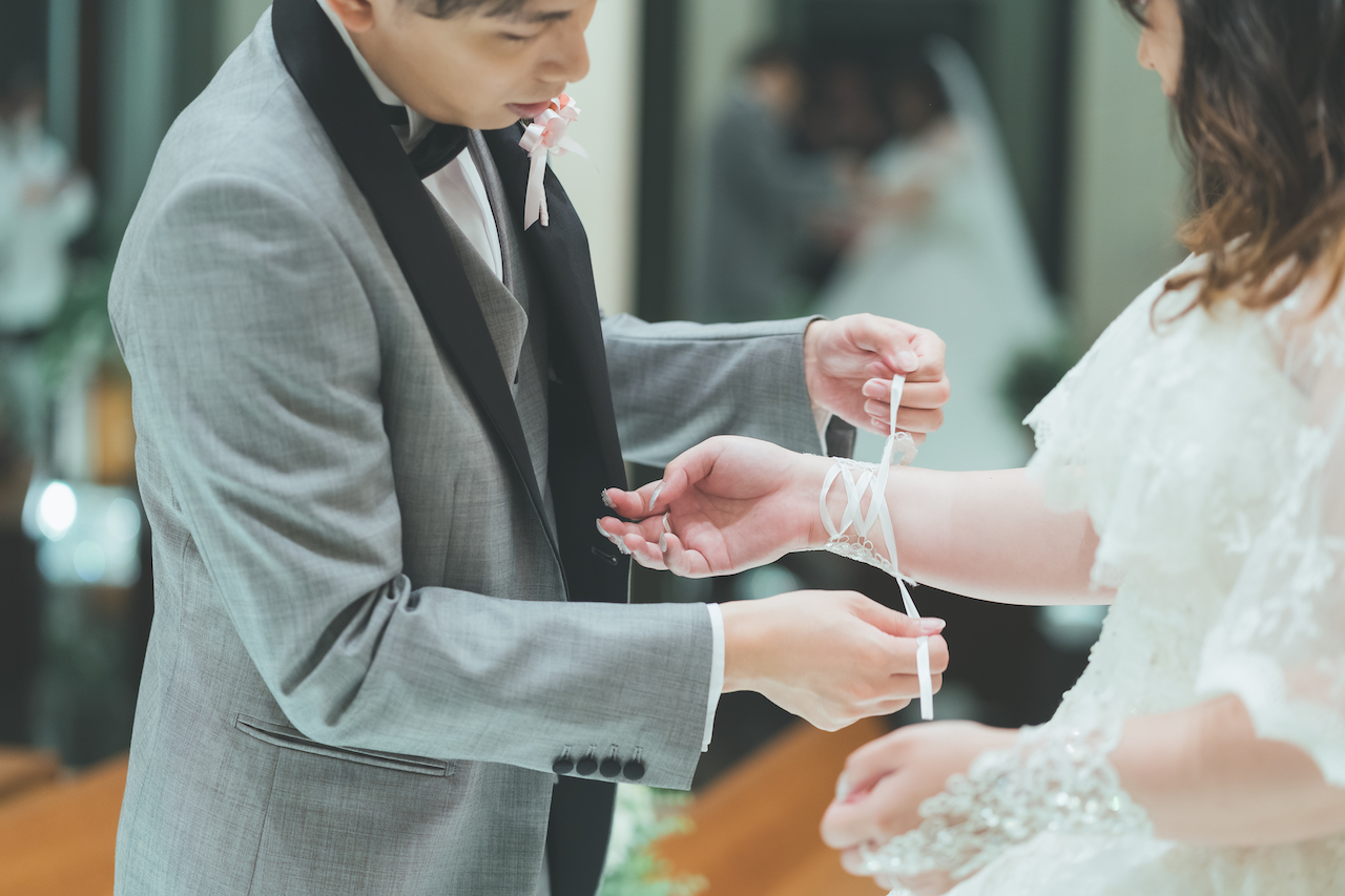 新郎が新婦のブライダルグローブの紐を結んでいる写真