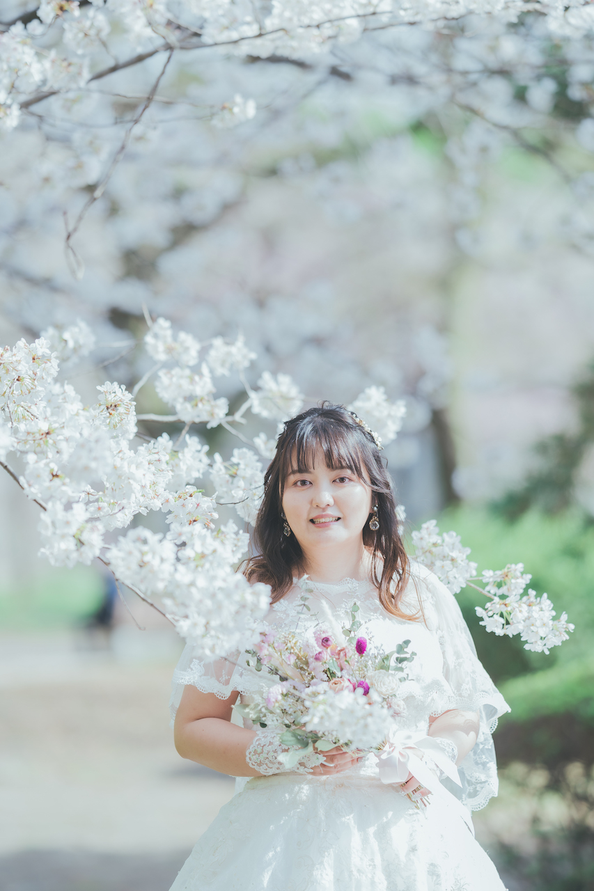 新婦が桜の中でにこやかにしている写真