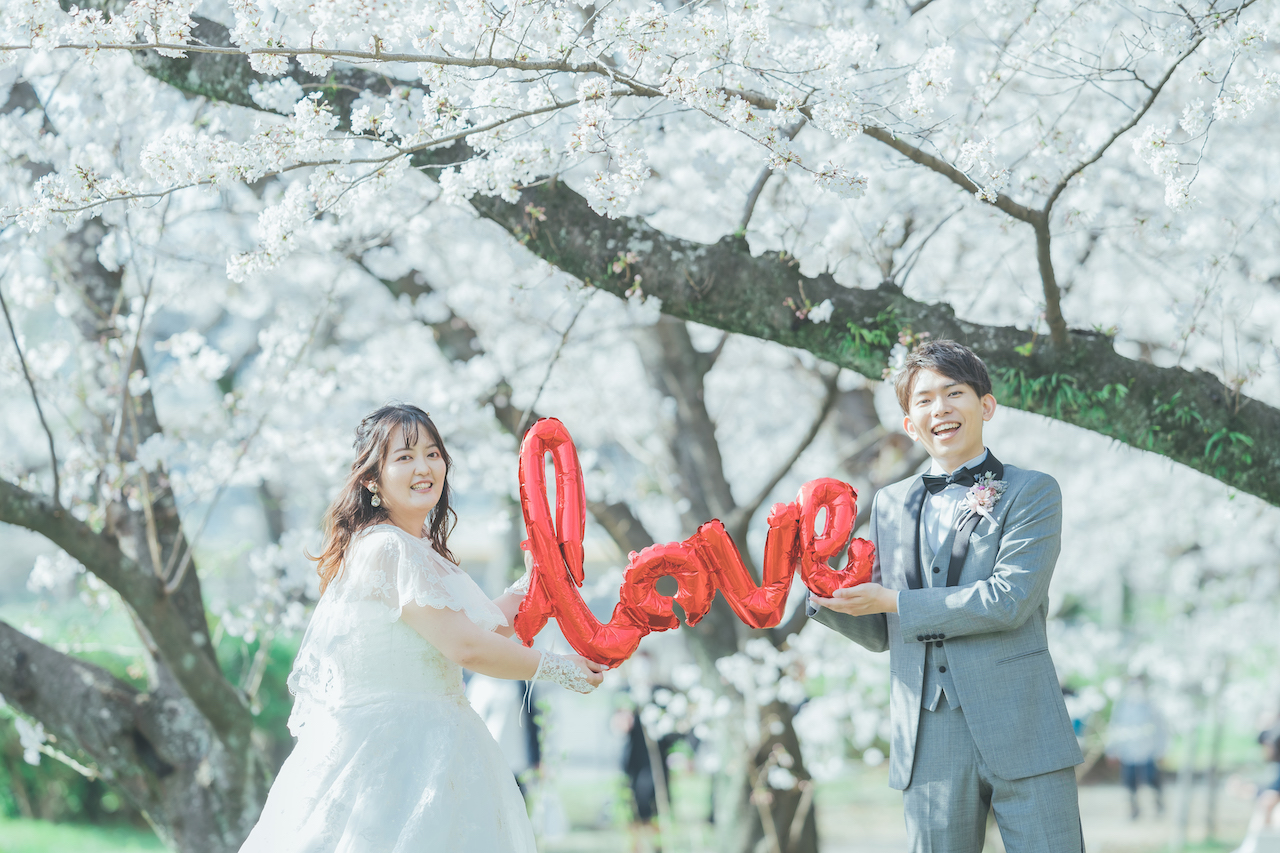 新郎と新婦が LOVE と書かれたバルーンを持っている写真