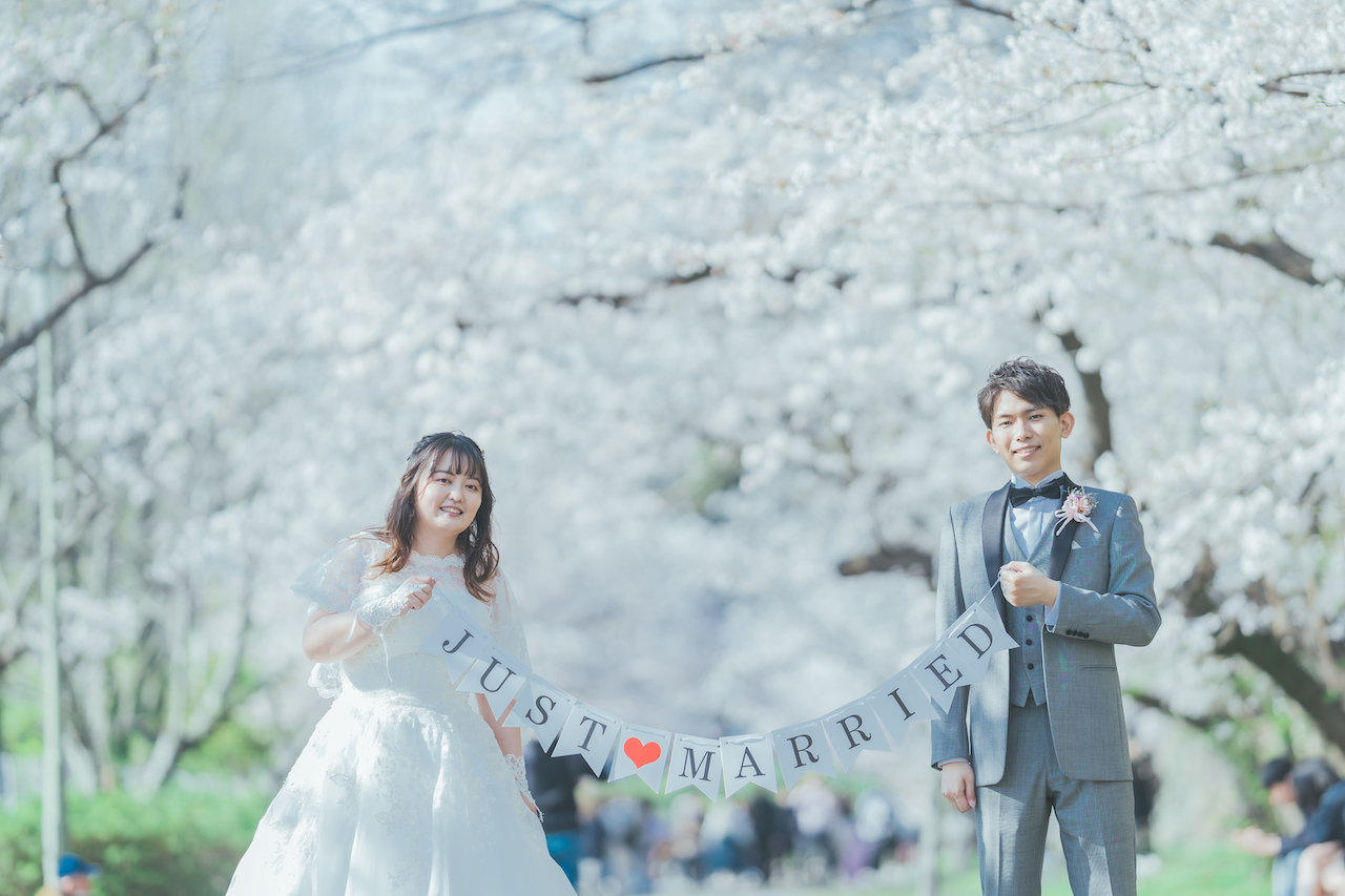 新郎と新婦が JUST MARRIED と書かれたホオジロバナーを持っている写真