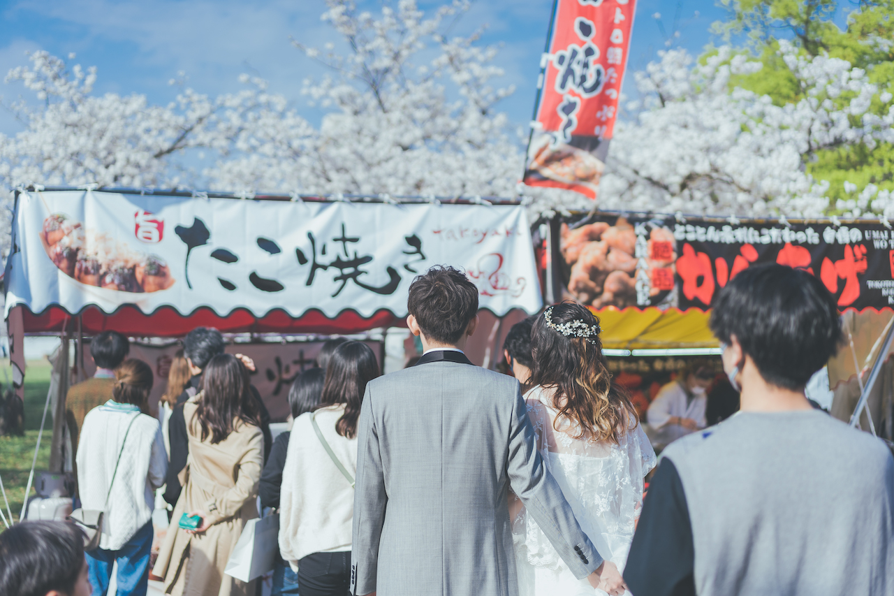 新郎と新婦がタキシードとウェディングドレスで屋台に並んでいる写真