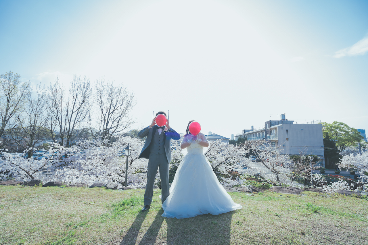 新郎と新婦が赤い風船を持って顔を隠している写真