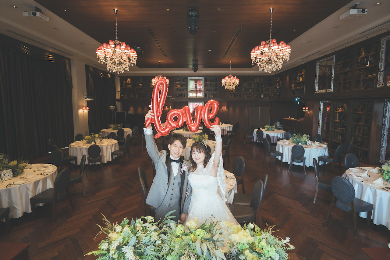 新郎と新婦が LOVE と書かれたバルーンを掲げている写真