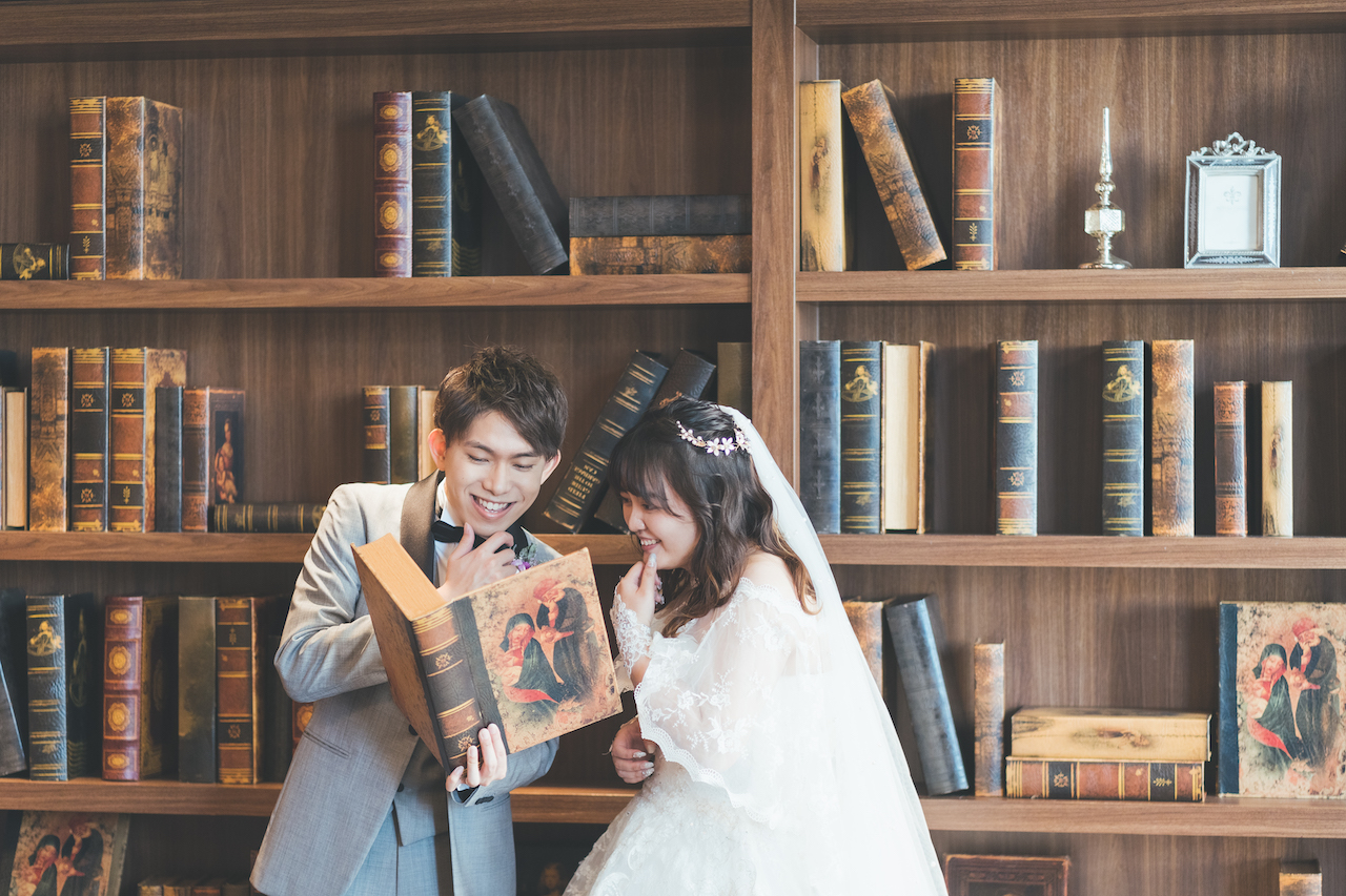 新郎と新婦が本棚の本を読みながら、ふたりとも顎に指をおいている写真