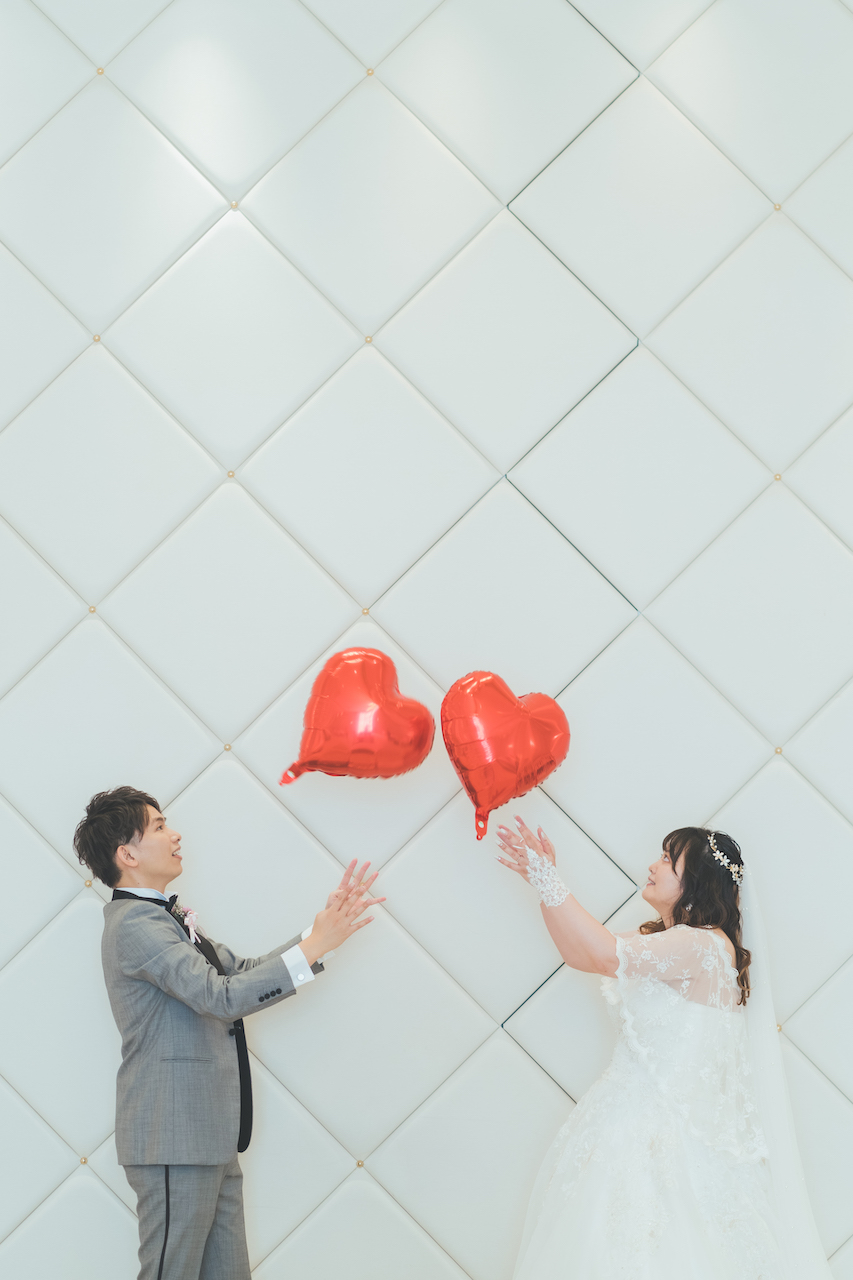 新郎と新婦が赤いハートのバルーンを跳ね合ってる写真